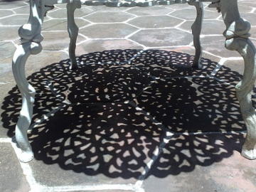 A photo of a  shadowy pattern cast by a table under the sunlight.