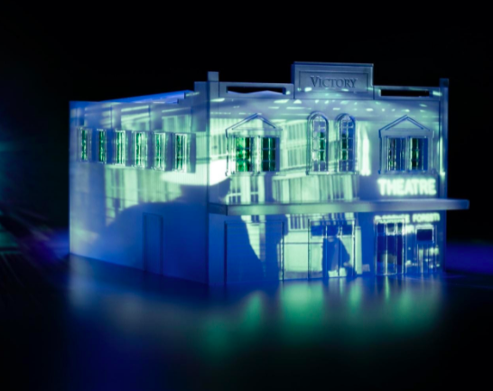 Model of a building with blue light projection on it.